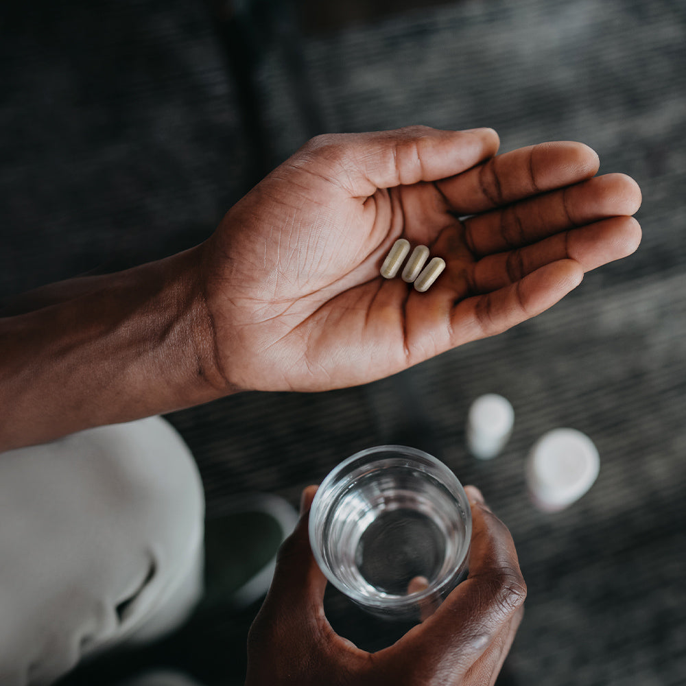 a hand holding 3 cleanse capsules